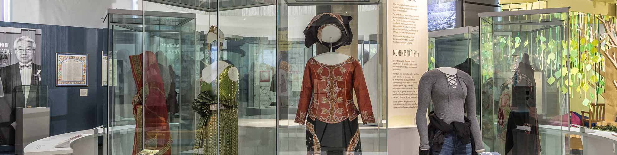 An image of the exhibition featuring mannequins with different clothes in a large glass case.