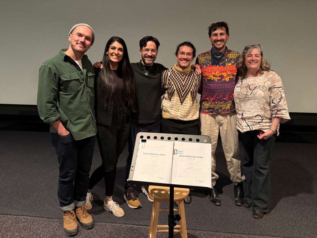 The cast posing with their arms around each other and smiling.