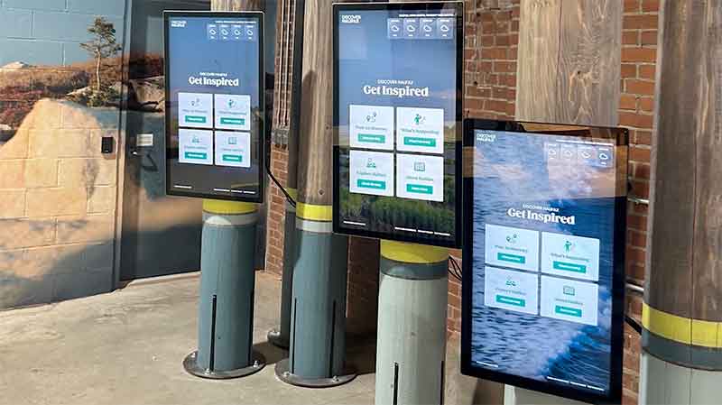 Three digital tourism kiosks installed on wooden pillars.