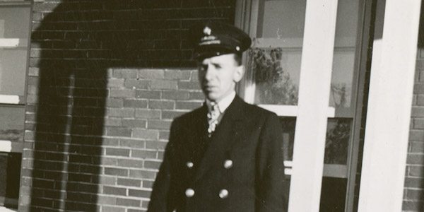 A man in hat and uniform looks at the camera.