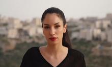 A portrait of Rana Nazzal Hamadeh against a blurred outdoor background, wearing a ponytail and red lipstick.