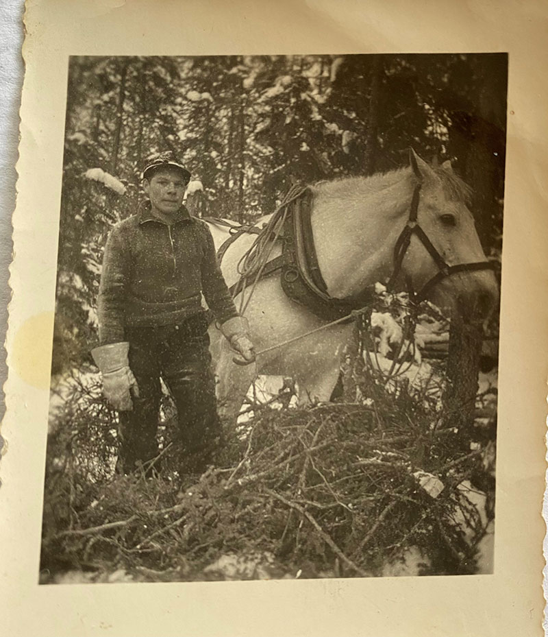Sepia photo of young man in the woods with a horse.