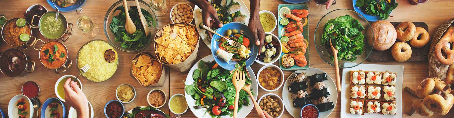 Curry, rice, seafood, salads, and breads from many cultures are laid out on a large table.