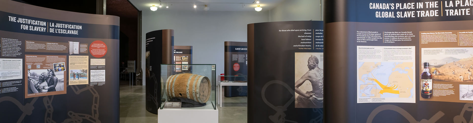 Exhibit panels with an image of a black man's deeply scarred back and text recounting the history of slavery in Canada.