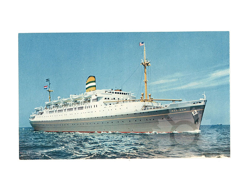 Colour photograph of TSS Maasdam at sea, seen from the starboard bow, with flags flying and a blue sky behind.
