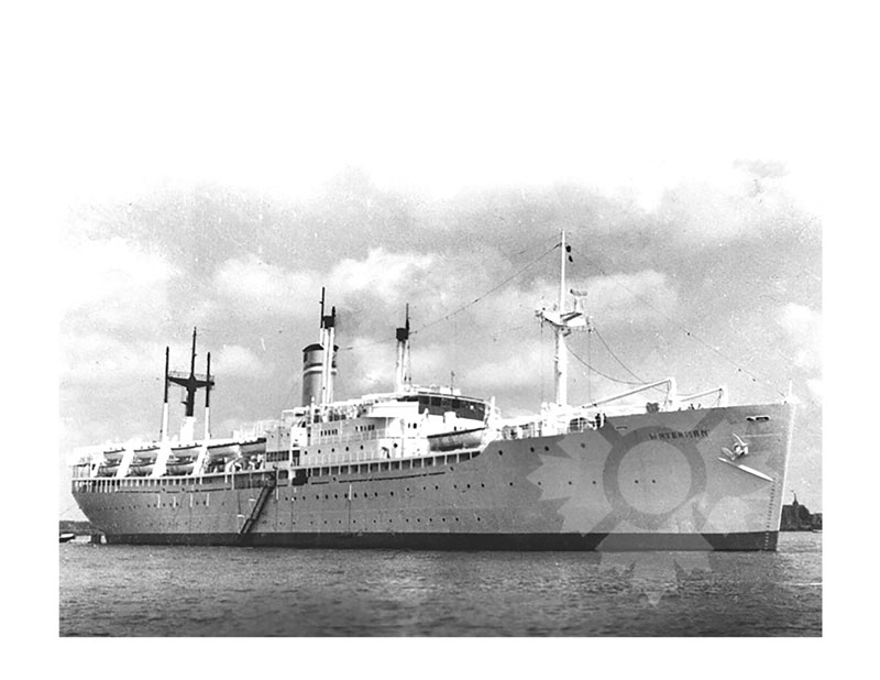 Black and white image of SS Waterman at anchor, seen from the starboard bow, with a cloudy sky behind.