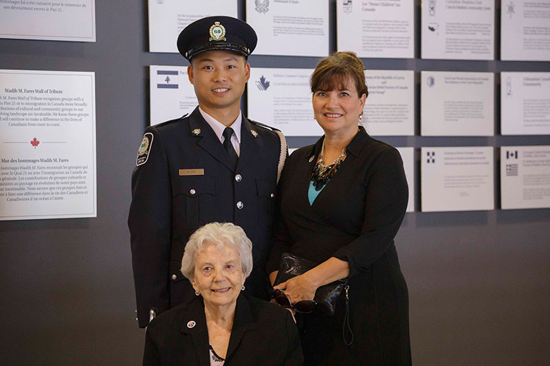A young man in police uniformstands next to two women.