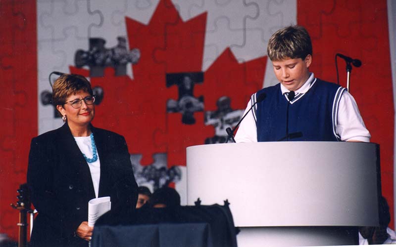 A woman is on stage and a young man is at the podium.