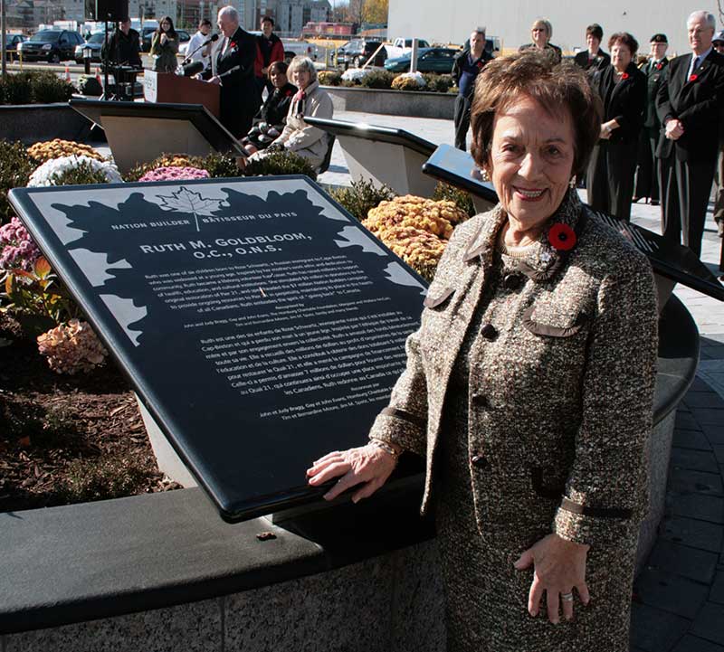 A woman stands in front of a standing marble plaque.