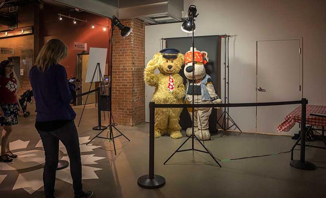 Woman takes picture of people dressed in mascot costumes.