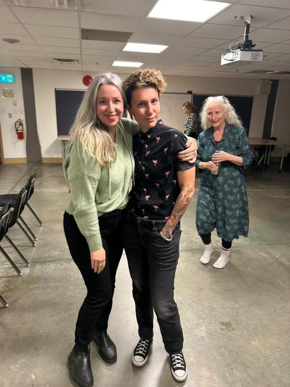 A portrait of Annie Valentina and a woman standing and smiling with an arm around each other.