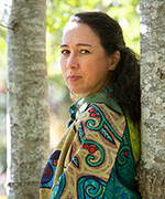 Portrait of artist shalan joudry leaning against a tree and looking into the camera.