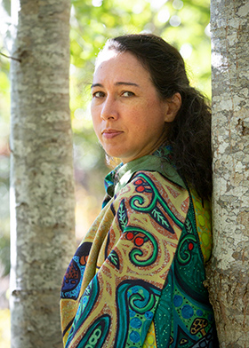 Portrait of artist shalan joudry leaning against a tree and looking into the camera.