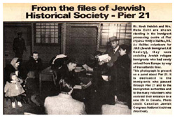 An article titled From the files of the Jewish Historical Society - Pier 21, with a photograph of people gathering around a man at a desk.