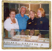 Four people pose together behind a museum display.