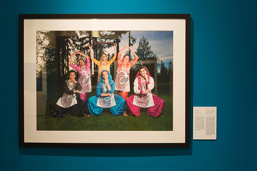 A framed portrait of six beautiful young ladies wearing traditional colorful dresses.
