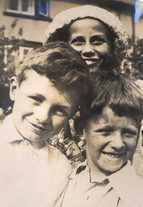 Two boys and a girl behind them smile for the camera.
