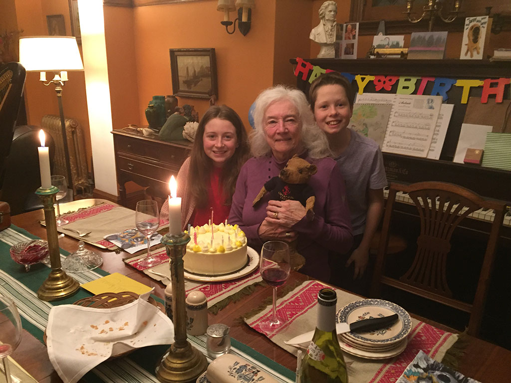 An older woman sits with a little boy and girl on either side of her.