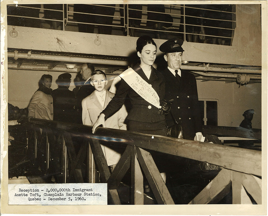 Danish immigrant Anette Toft walks down a gangway from SS Batory. Behind her is Toft’s younger brother. In the distance is Canadian immigration officer William McFaul, Champlain Harbour Station, Quebec City.