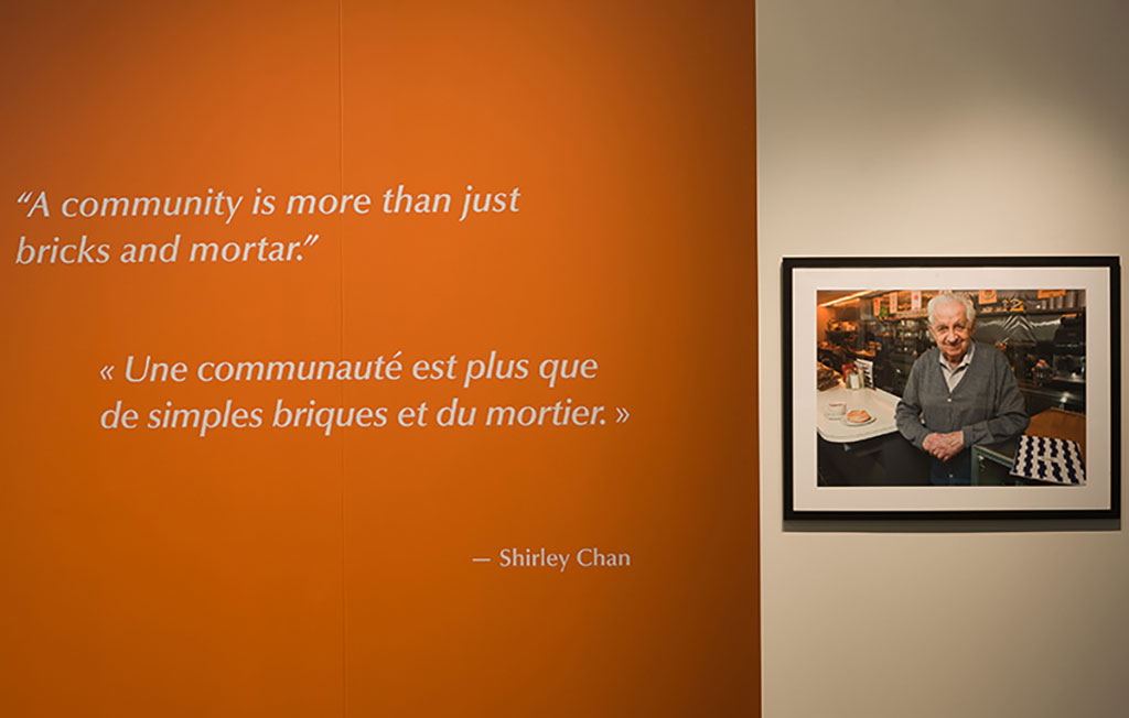 An orange wall with a framed portrait of an elderly man hanging on it.