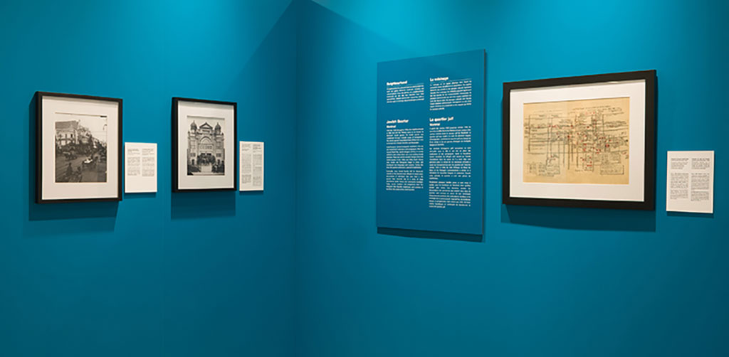 Two sections of a teal-coloured wall, with frames of varying size showing text and images.