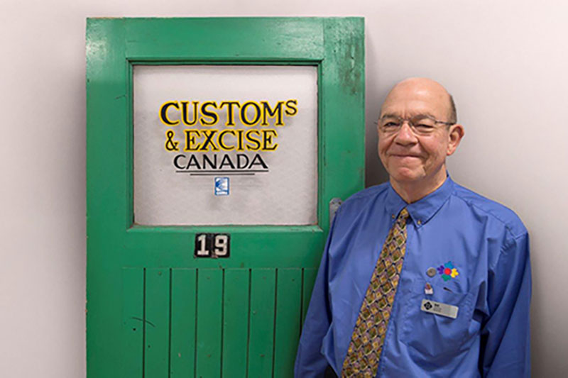 Smiling man stands next to a green door.