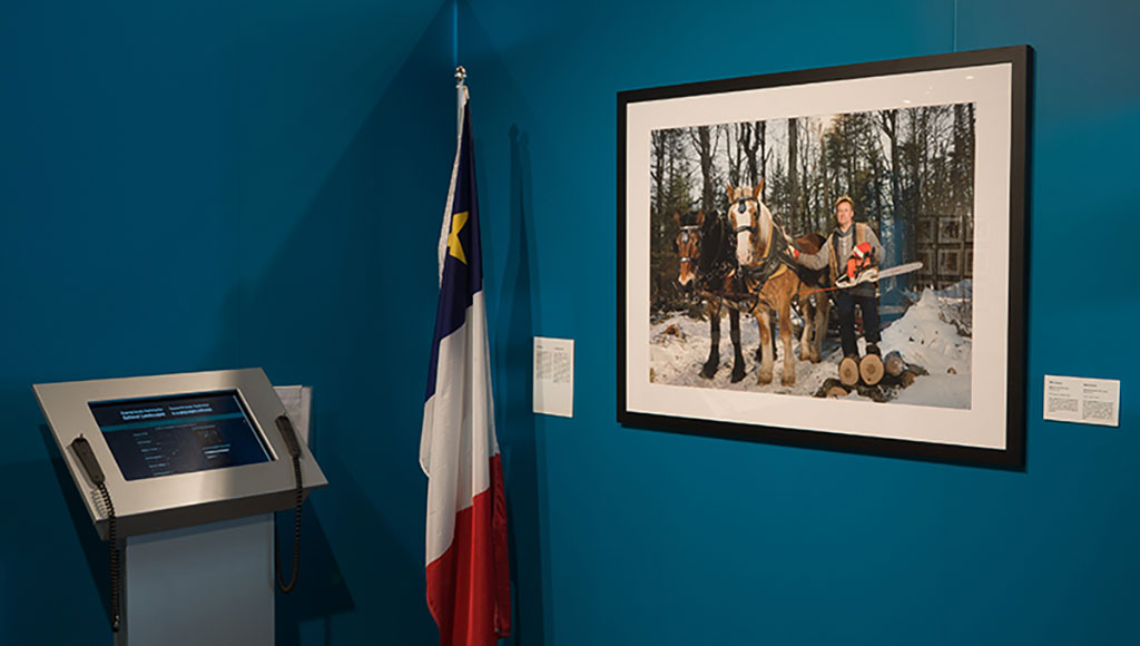 A large portrait of a man standing in the snow with workhorses and a chainsaw hangs on the wall.