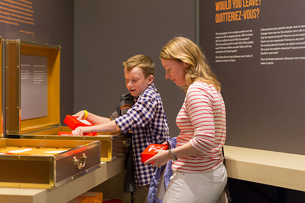 A young woman and girl look into a suitcase activity.