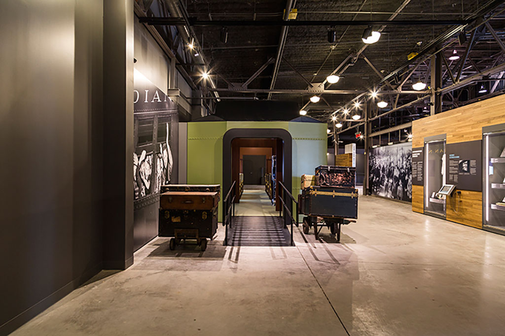 Luggage trunks and bags sit in front of a replica of a train.