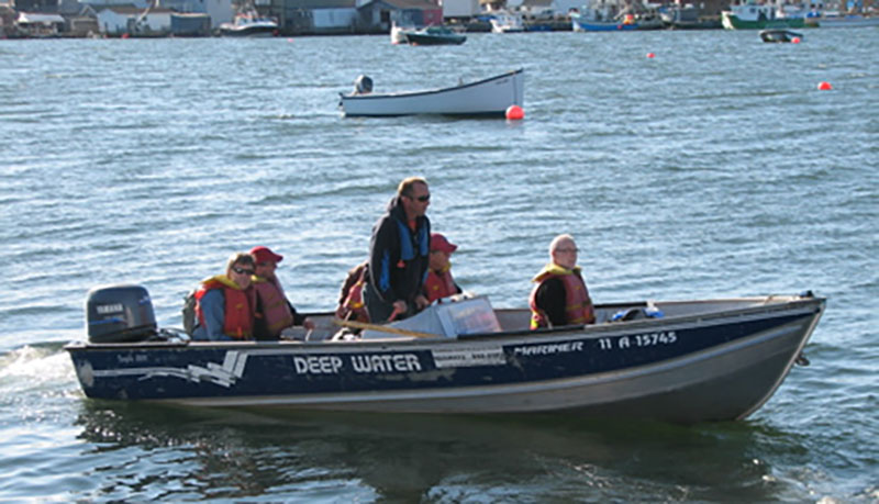 People wearing life vests are in a moving speedboat.