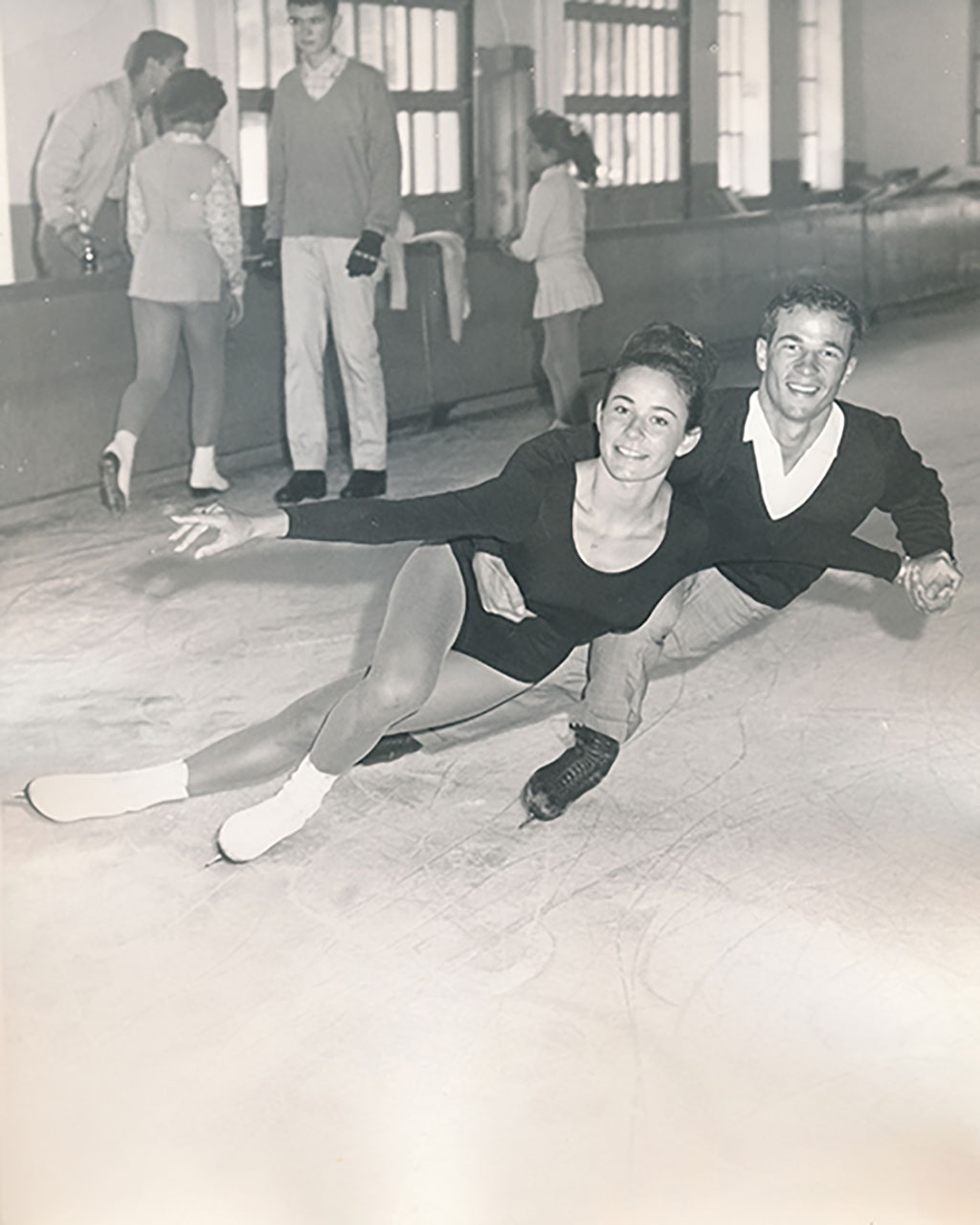 An archival black and white photo of a beautiful young couple doing figure skating.