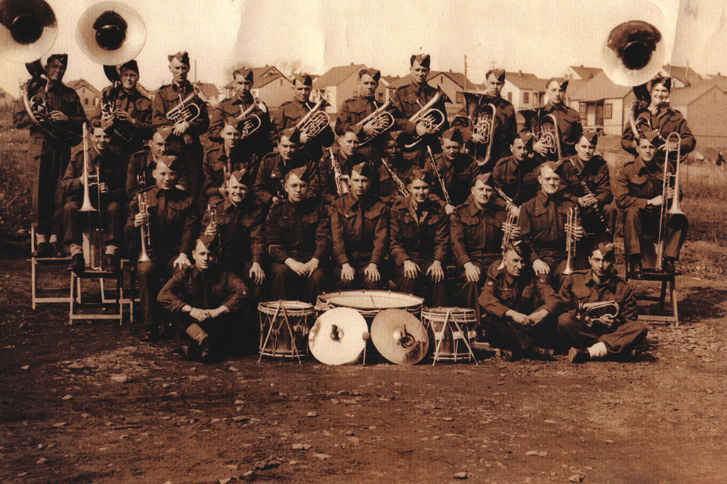 Archived sepia portrait of a large military band, some men are sitting and some are standing.