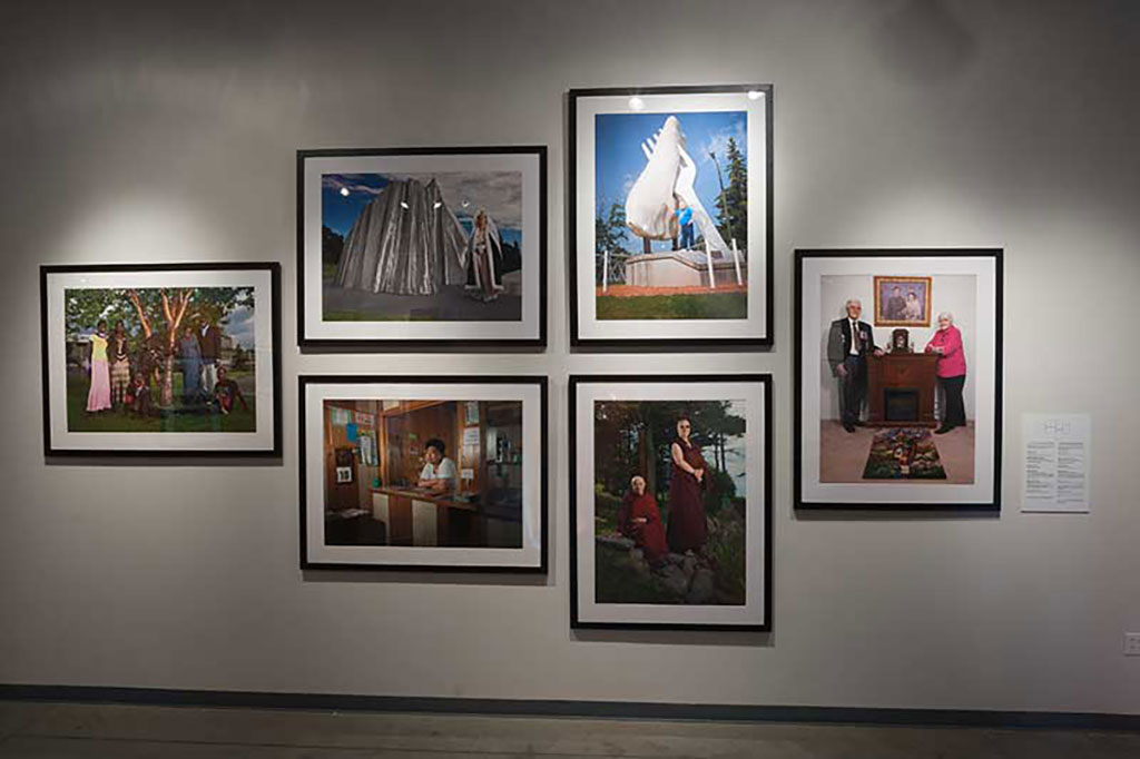 Many large colourful photos are framed, hanging on a wall.