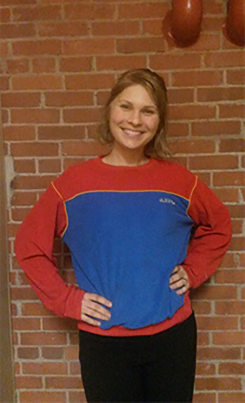 Kristine Kovacevic , Manager of Interpretation and Visitor Experience stands wearing a red and dark blue sweatshirt.