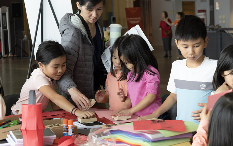 A group of young Asian children participating in crafts at a table in the Museum.
