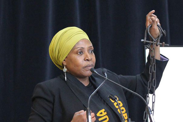 Dr. Afua Cooper holds up heavy iron shackles.