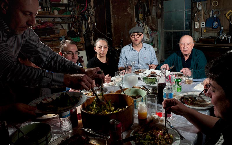 A family sits around a table to eat, and one person serves food onto a plate.