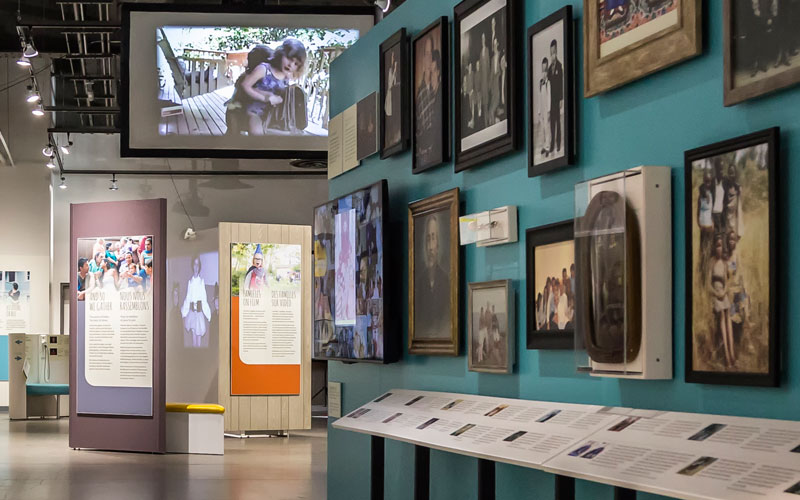 An image of the exhibition featuring framed family photos on the wall and exhibition panels.