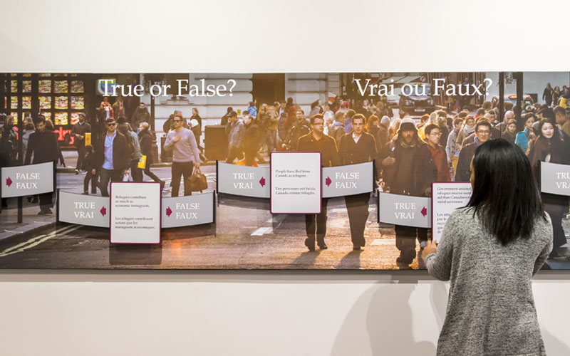 A person stands in front of an exhibition panel that says “True or false?”