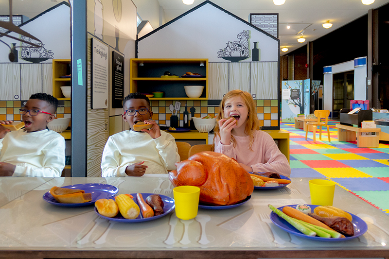 A young boy and girl pretend to eat plastic food.