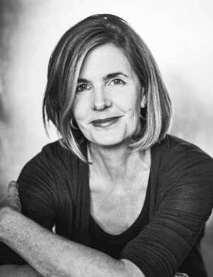 A black and white portrait of a white woman smiling at the camera.