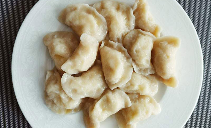 Perogies served on a white plate, shot from above.