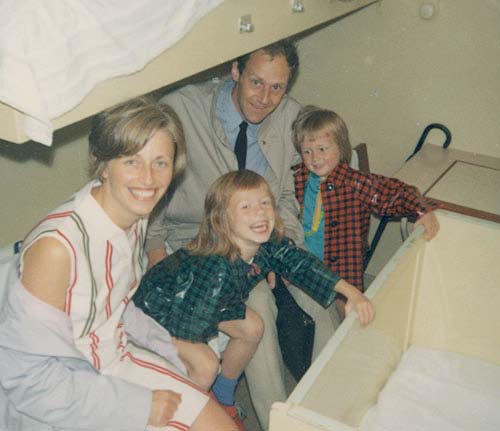 Family of four smiling at the camera sitting on a bottom bed aboard the SS Maasdam