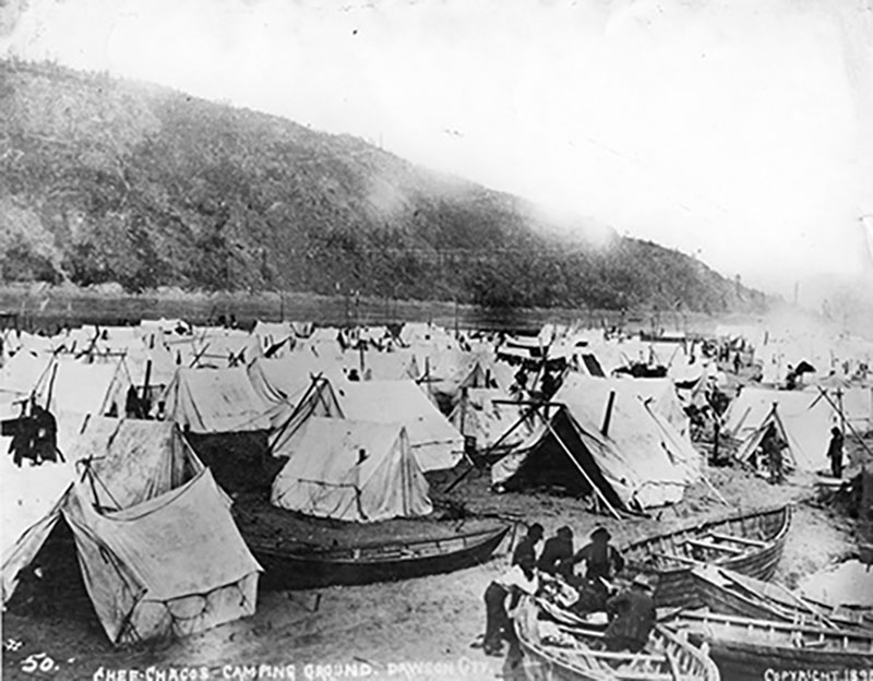 A large number of tents sit at the base of a mountain.