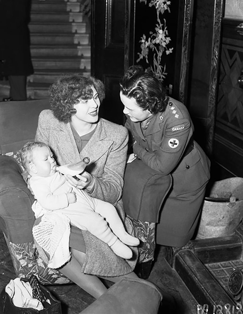 A woman in uniform helps a mother and baby.