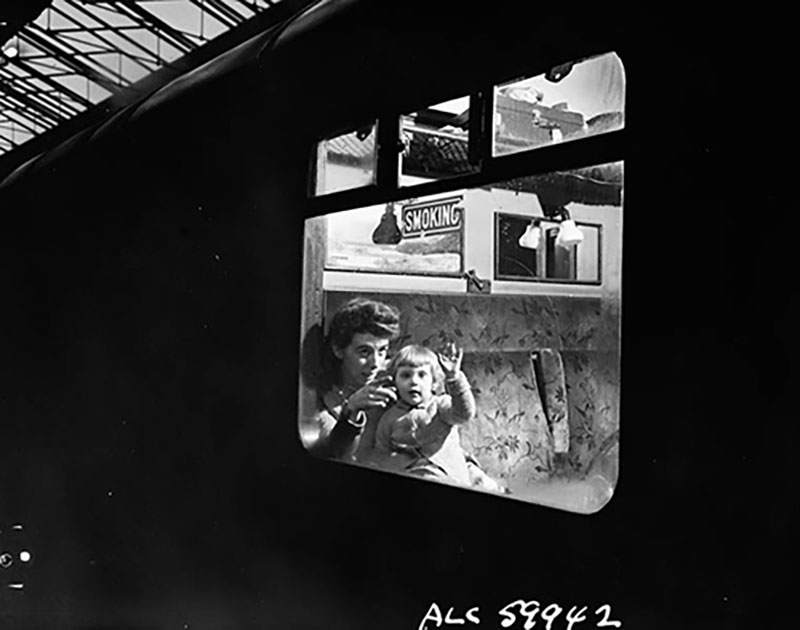 A woman and her small child peer out of the window of a train.