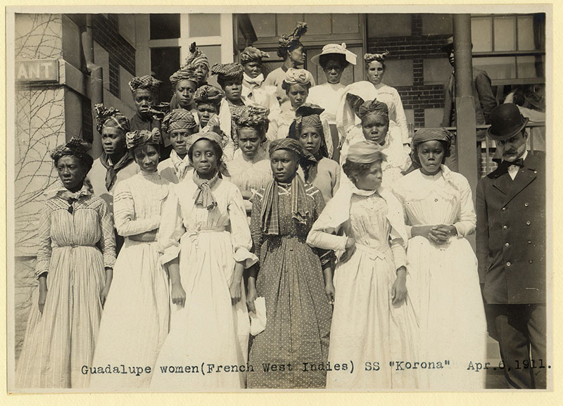 Twenty-two women in dresses and one man in a suit look at the camera.