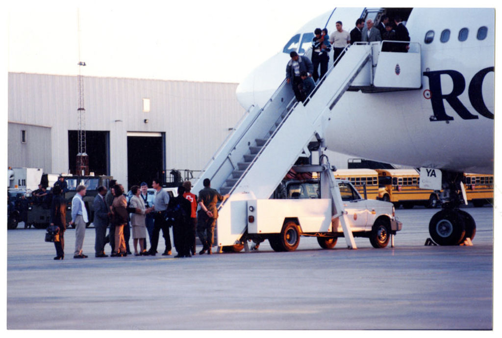 A group of people are descending from an airplane via stairs.