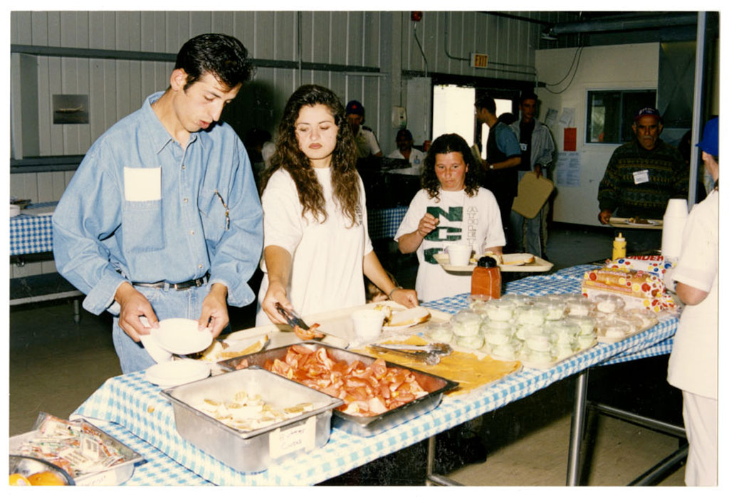 A group of people are filling plates with food from a long table of food.