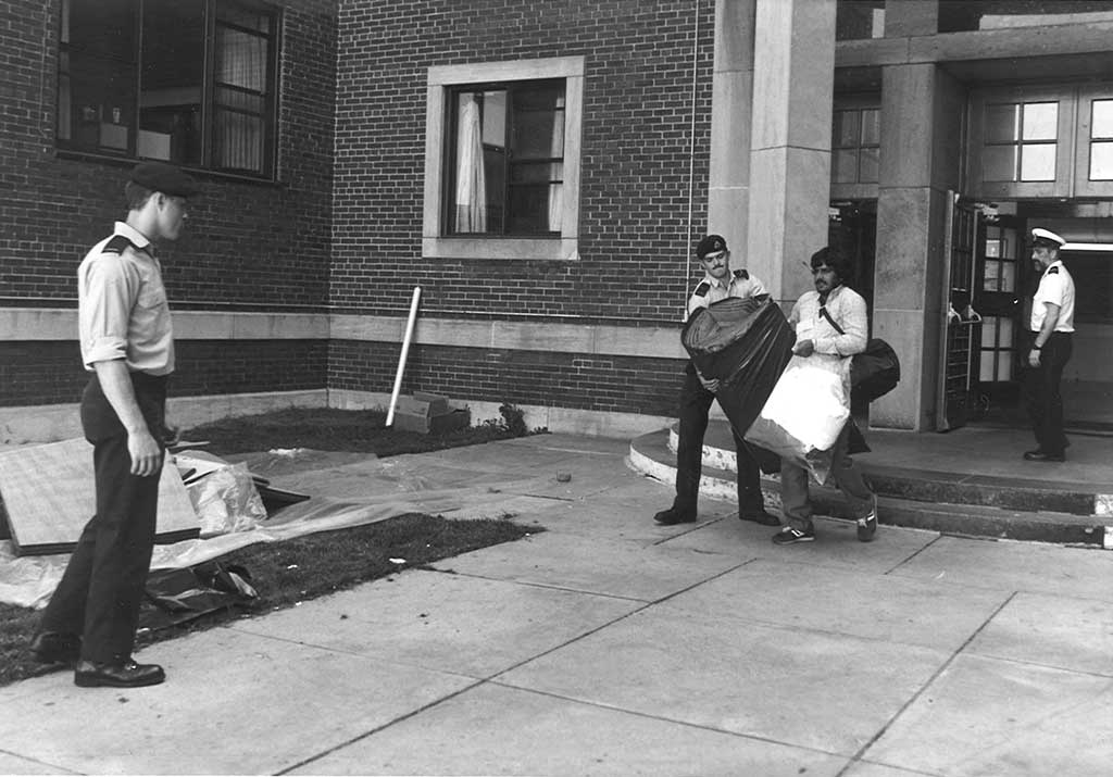 A young man in military uniform helps another man with carrying his baggage.